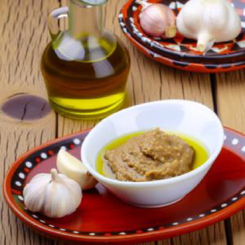 Bowl of Albanian garlic sauce drizzled with olive oil and fresh herbs