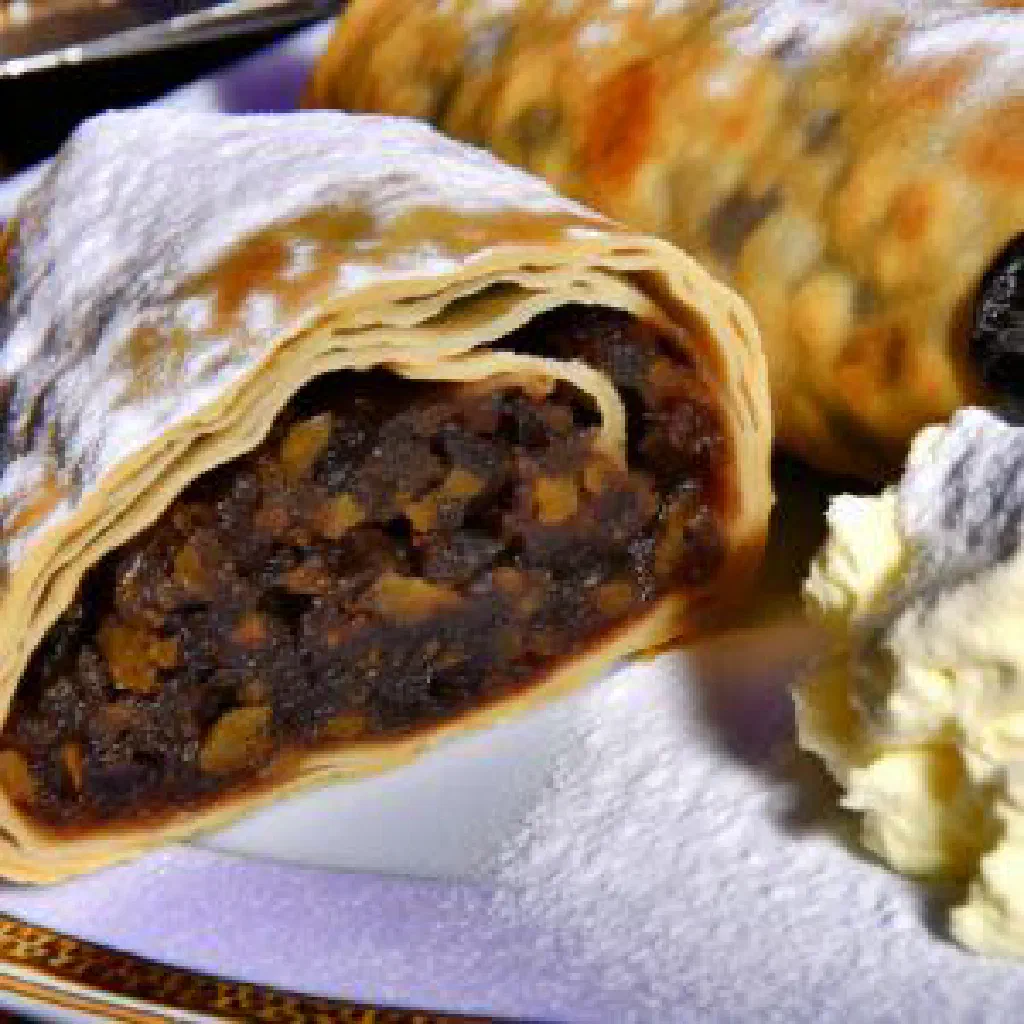 Sliced plum jam strudel dusted with icing sugar on a plate