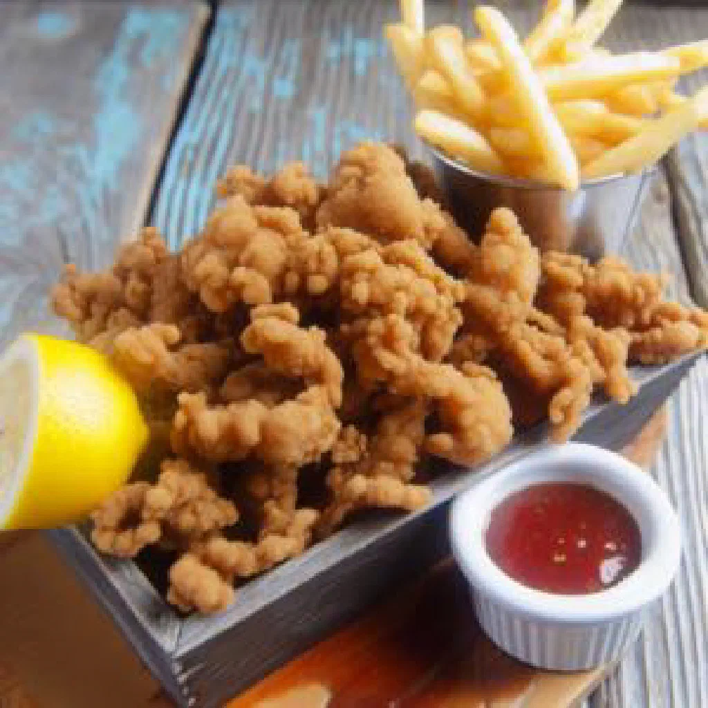 Golden fried cracked conch pieces with lime and tomato salsa