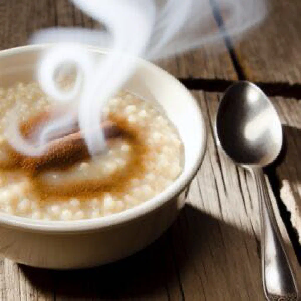 A steaming cup of warm Bolivian api corn drink with a cinnamon stick