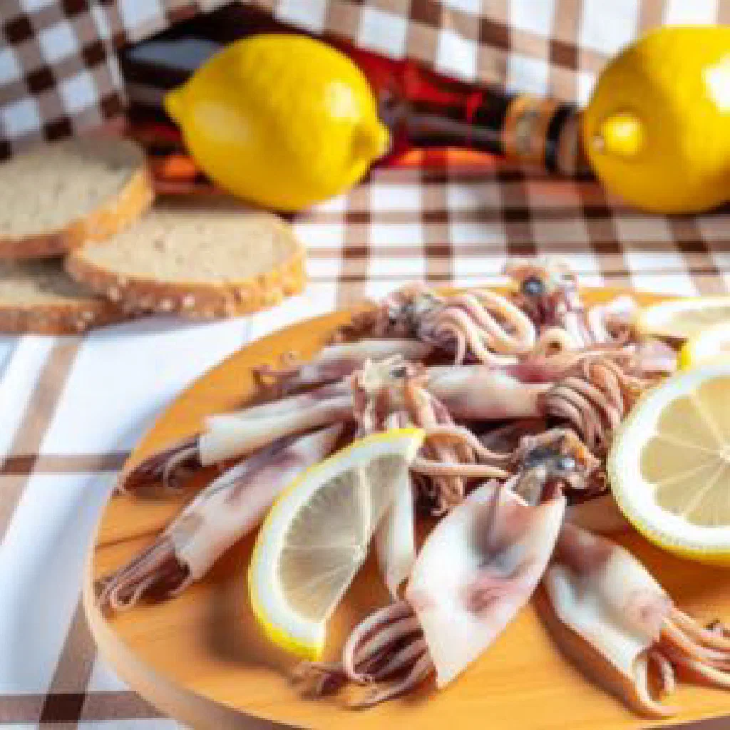Pan-fried dried squid with garlic and herbs on a plate with lemon