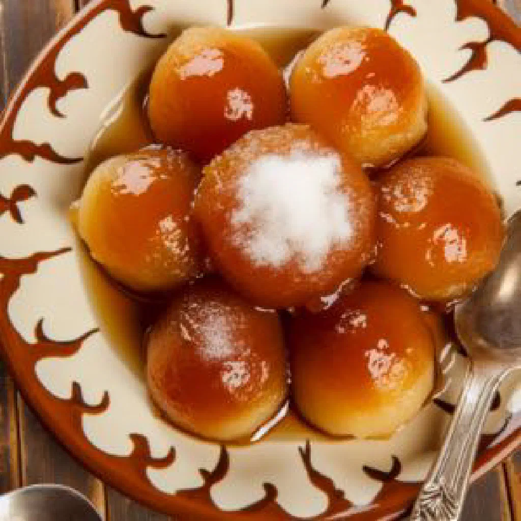Golden Loqmet El Qadi dough balls glazed with syrup on a plate