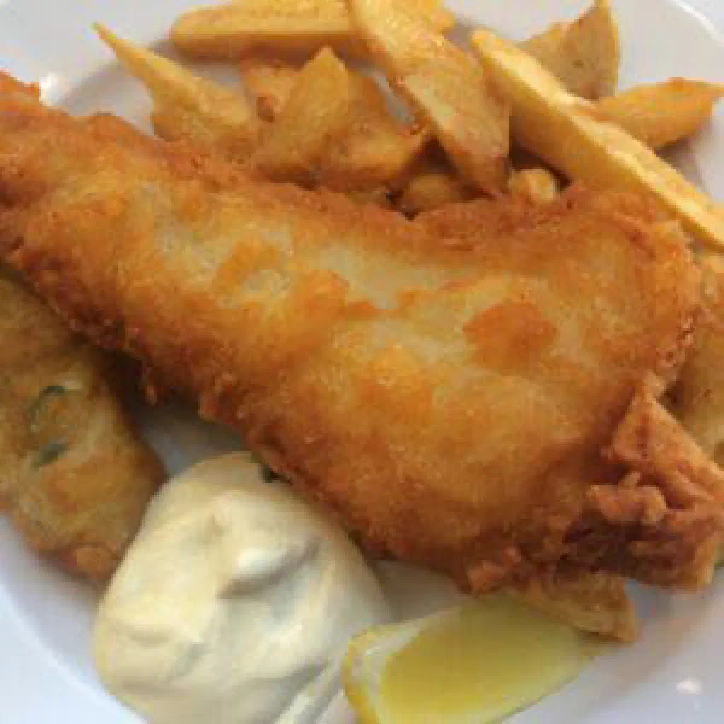 Golden battered fish with a pile of chunky chips