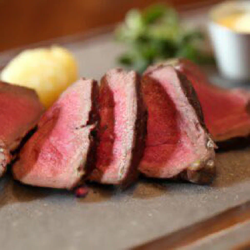 Sliced Chateaubriand beef fillet fanned out with red wine sauce and fresh herbs