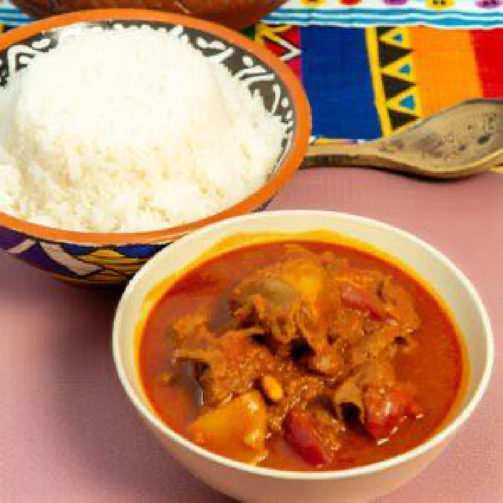 Bowl of Gambian mafe peanut stew with meat and vegetables served over rice