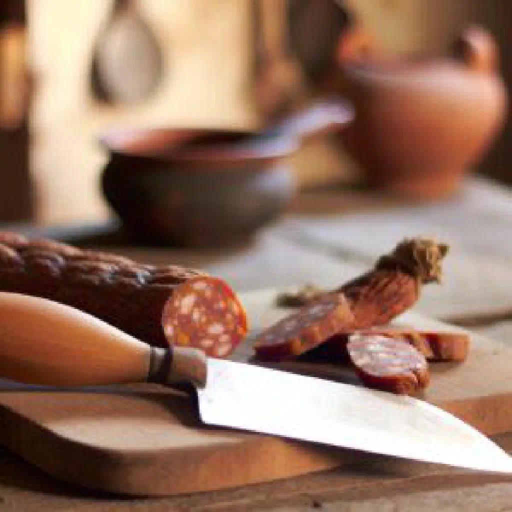 Grilled loukaniko sausage coils garnished with orange slices and herbs