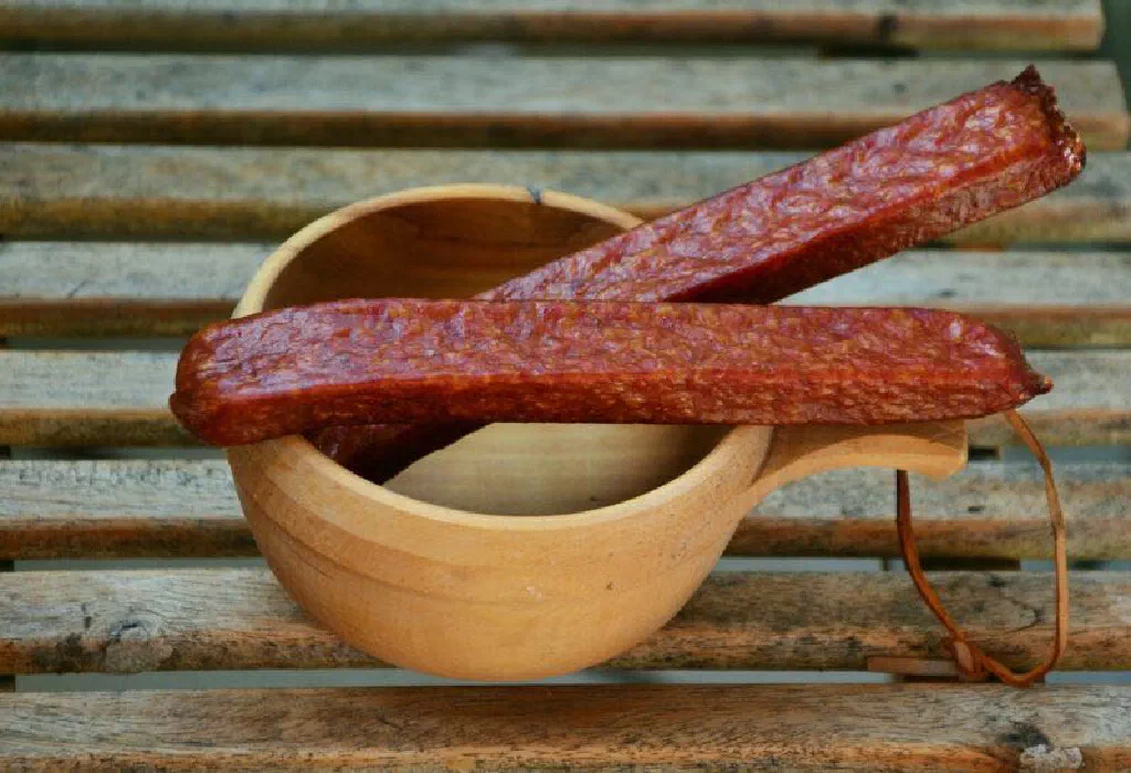Pair of air-dried Landjäger sausages on a rustic wooden board