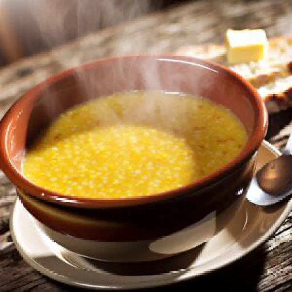 A smooth mound of Malian tô served in a bowl with sauce alongside