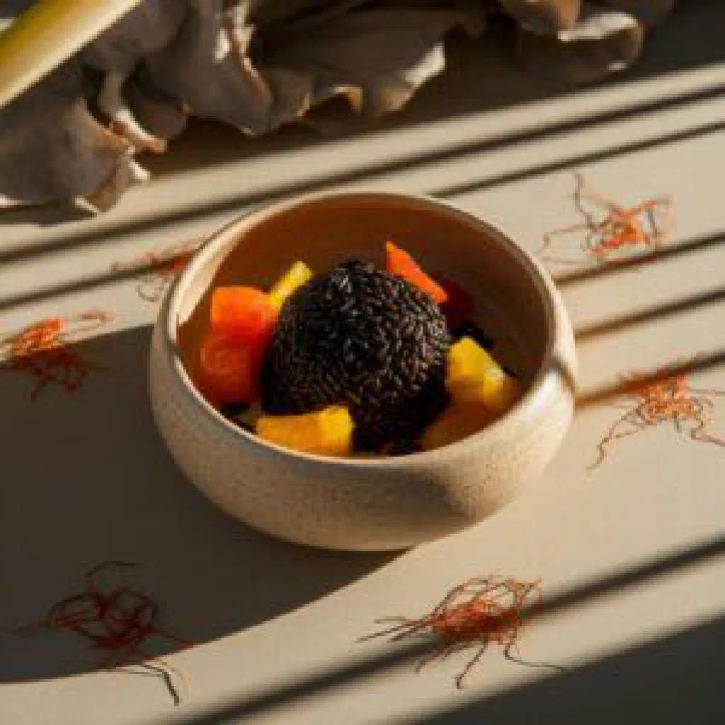 Bowl of Mauritian black rice with seafood and fresh herbs