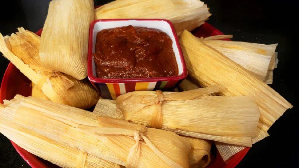 Steamed tamales wrapped in corn husks served with salsa