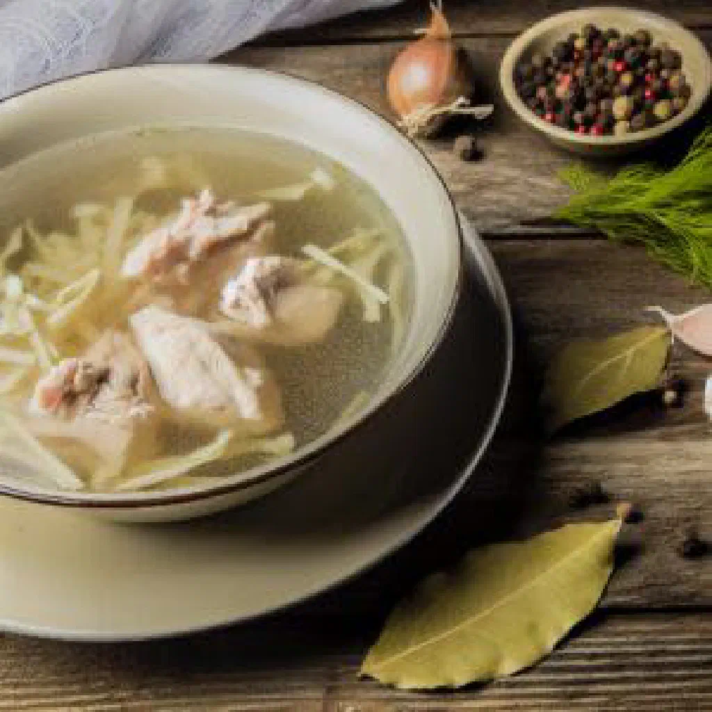 Bowl of Moldovan chicken noodle soup with carrots and fresh parsley