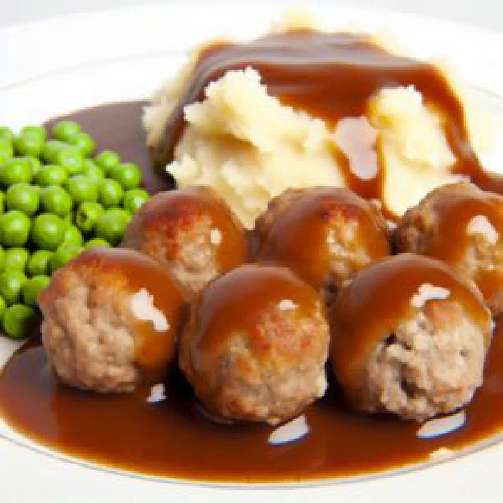 Golden-brown Norwegian medisterkaker pork patties served with potatoes and gravy