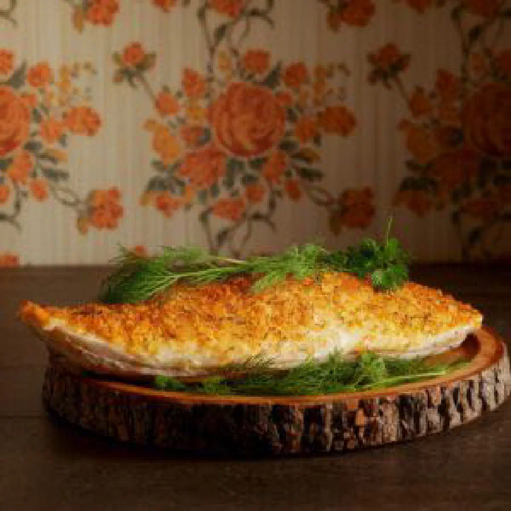 Golden breaded pike-perch fillets garnished with fresh herbs and lemon