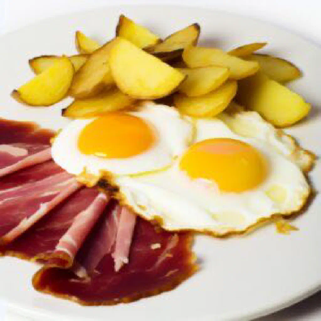 Huevos rotos with runny fried eggs over crispy potatoes and Iberico ham
