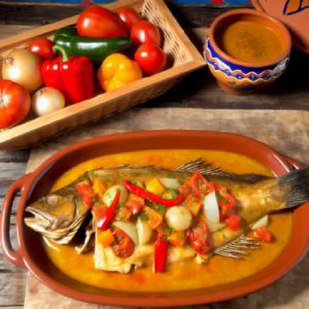 Baked monkfish with peppers, tomatoes and herbs in a roasting dish