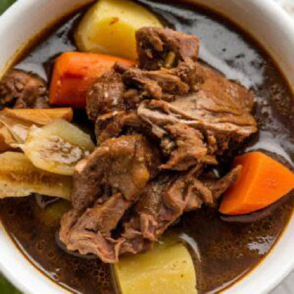 Bowl of Caribbean goat water stew with tender goat meat and vegetables