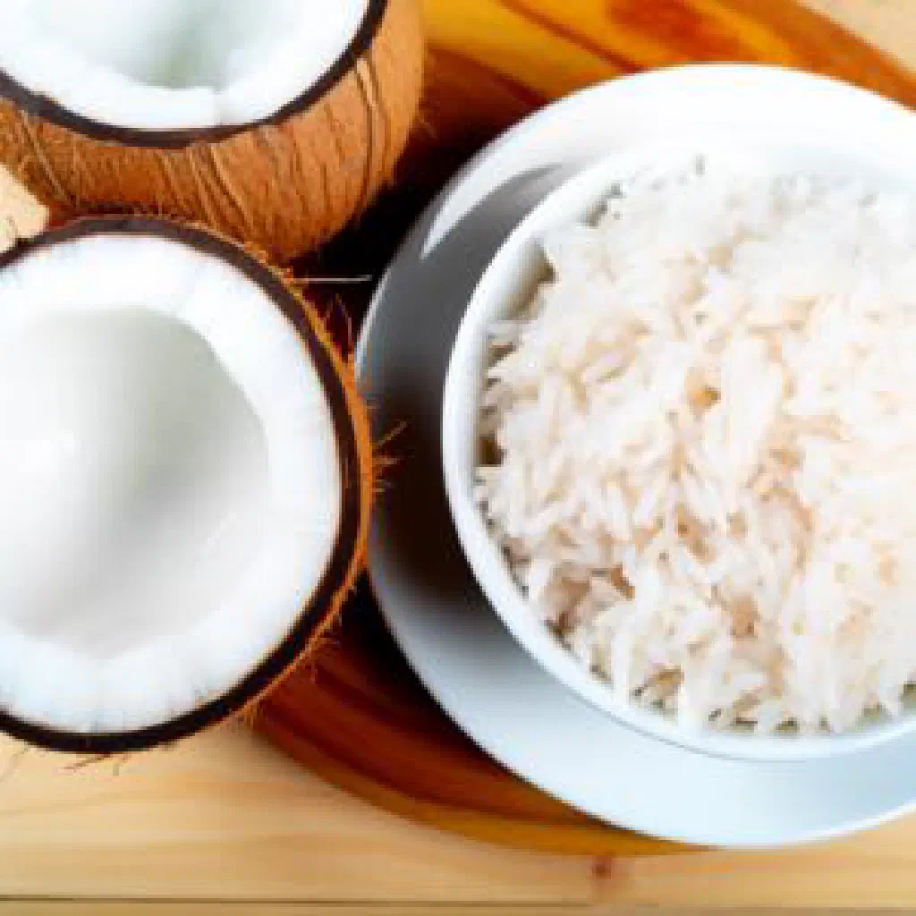 Fluffy coconut rice in a bowl, garnished with fresh herbs and lime