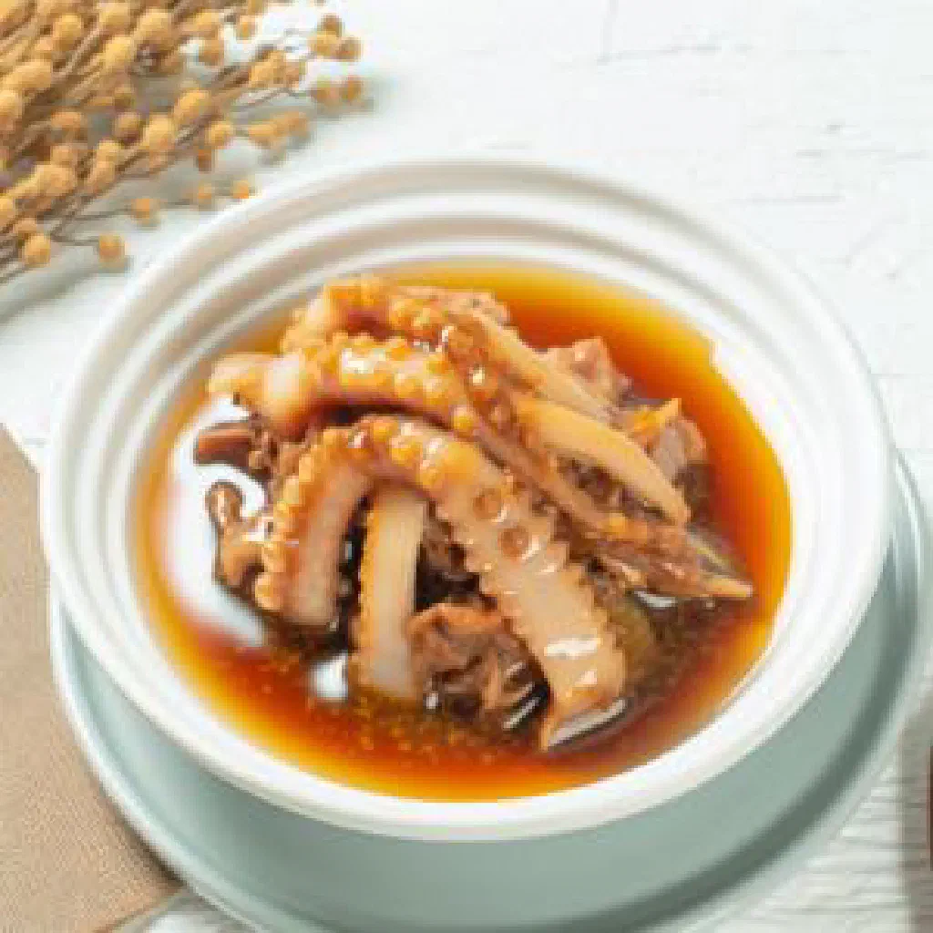 A steaming bowl of cuttlefish geng garnished with fresh coriander