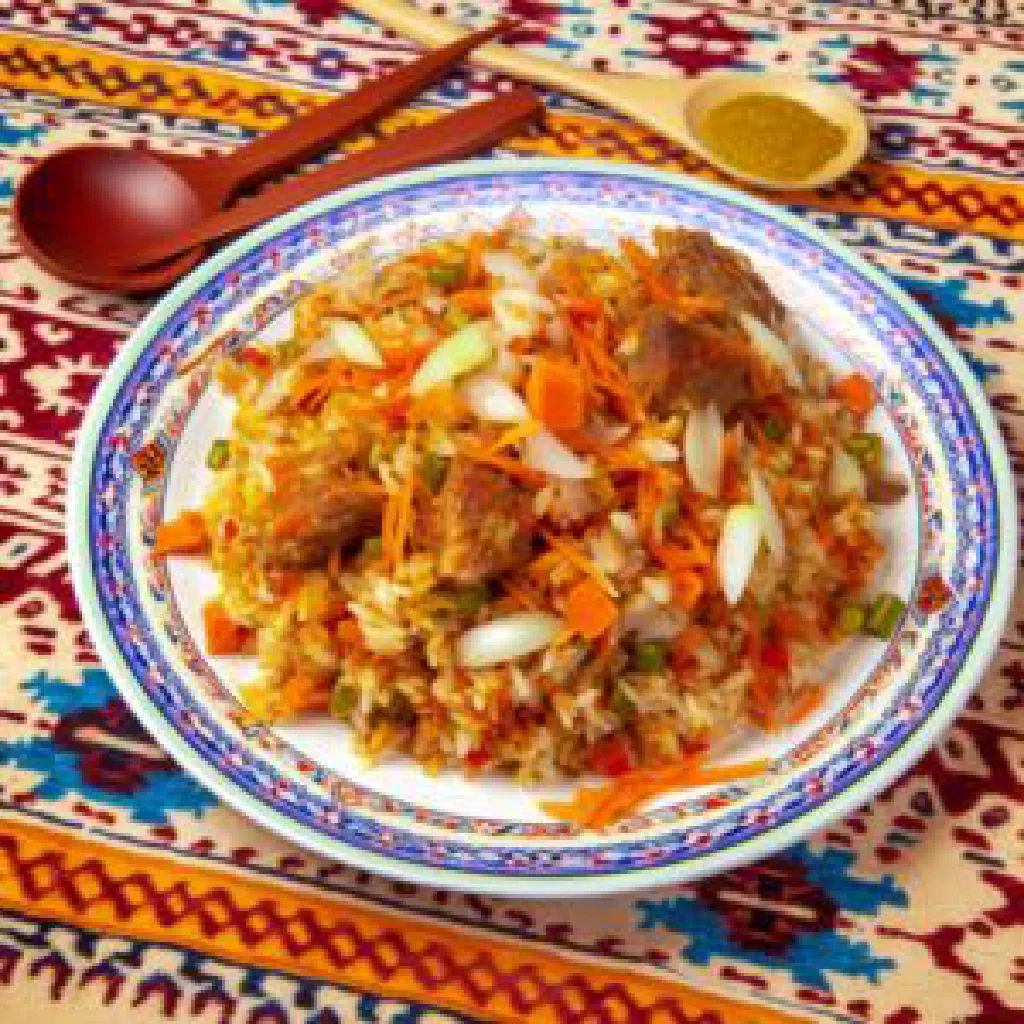 Osh rice pilaf with lamb, carrots and fresh herbs in a traditional bowl