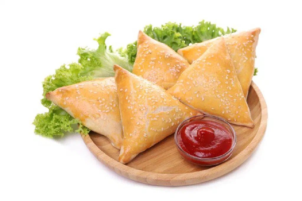 Golden fried Tanzanian samosas on a plate with fresh coriander