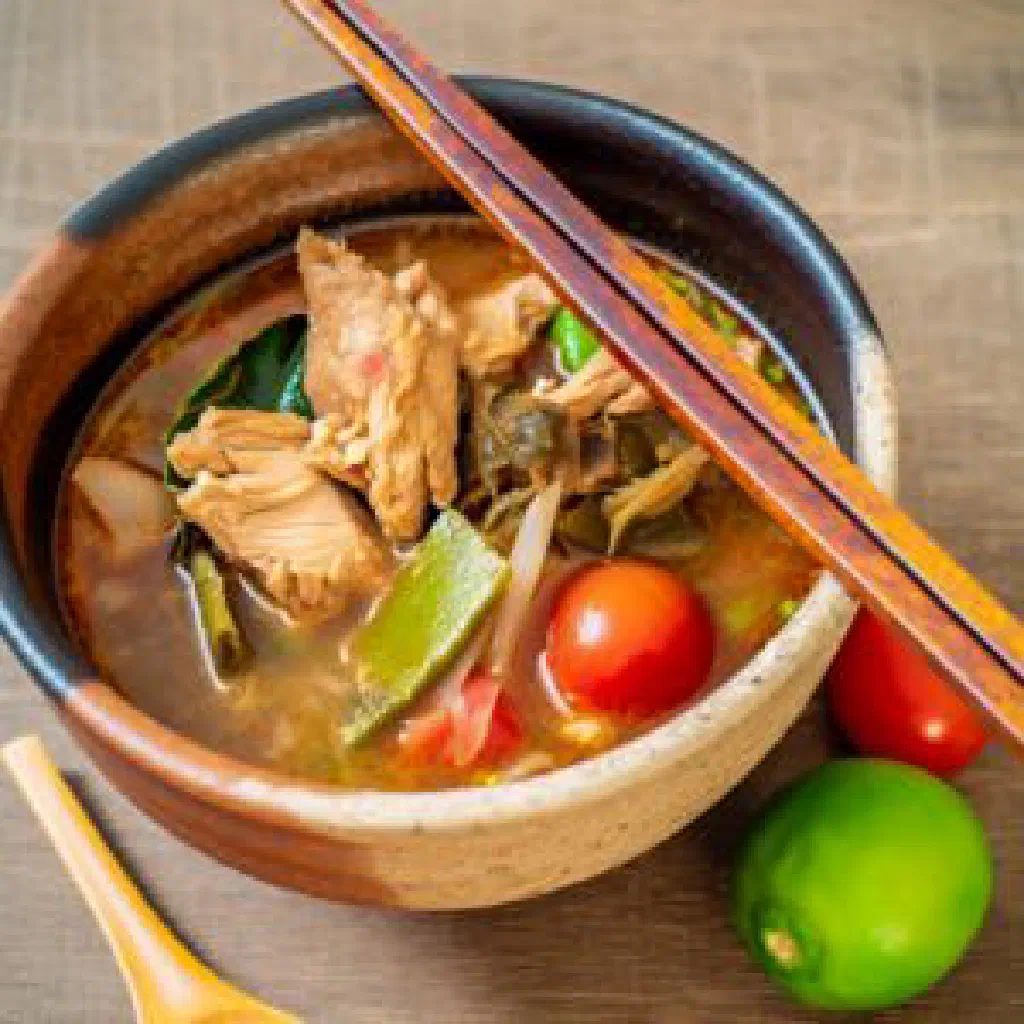 A steaming bowl of Tom Jiew Gai chicken soup garnished with fresh coriander