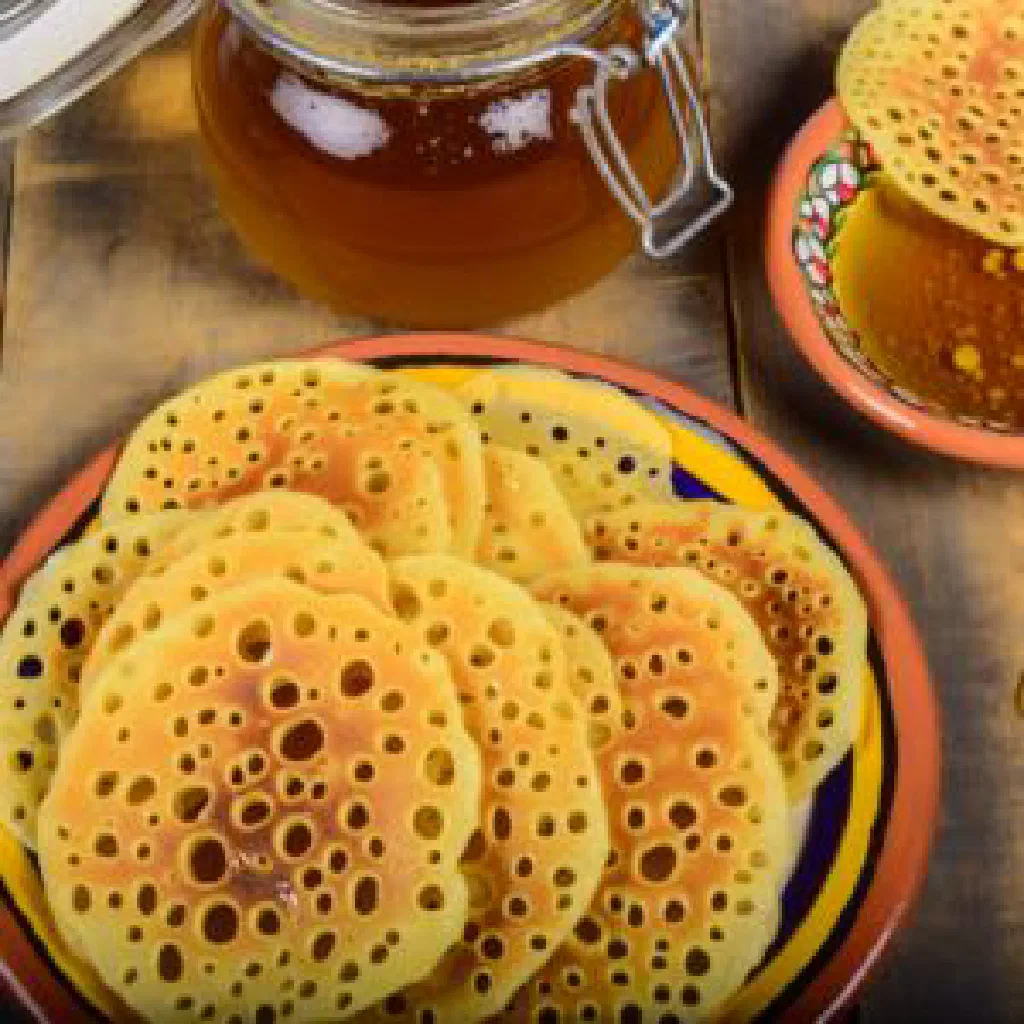 A stack of airy Tunisian baghir pancakes drizzled with honey