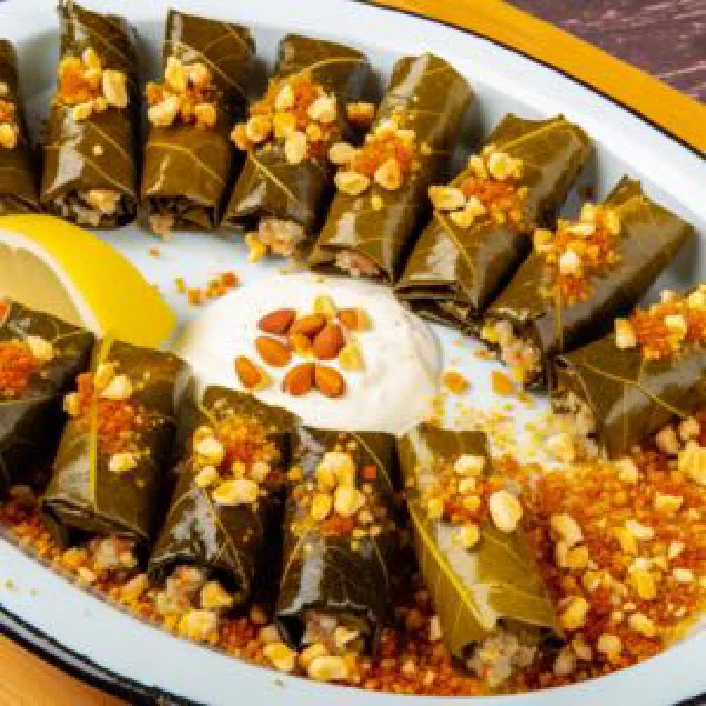 Hazelnut stuffed vine leaves arranged on a plate with fresh herbs