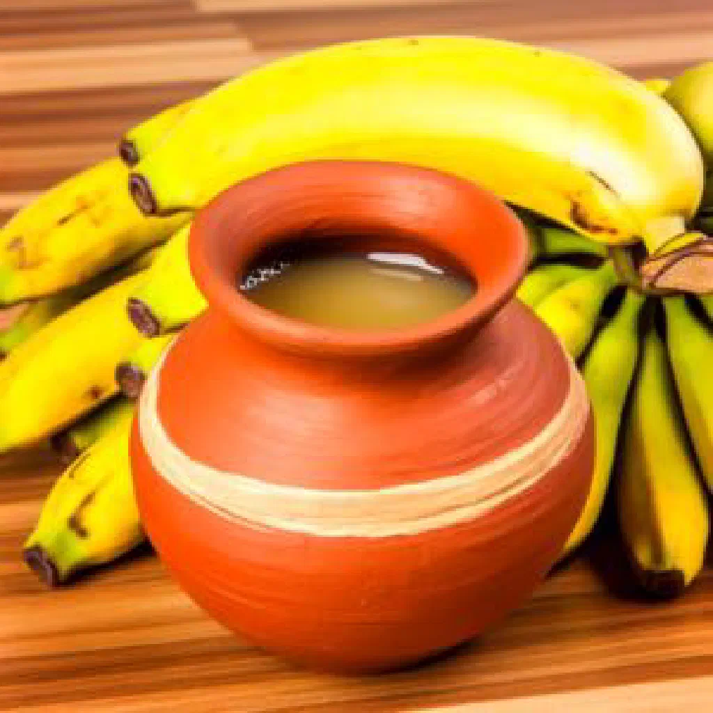 Glass of golden Ugandan banana wine served with ripe bananas