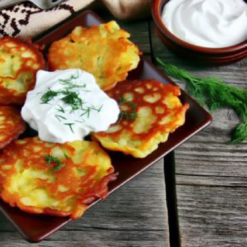 Golden crispy Ukrainian deruny potato pancakes served with a bowl of sour cream