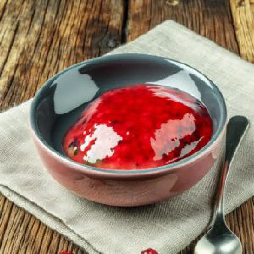 A glass of ruby-red kisil garnished with fresh berries