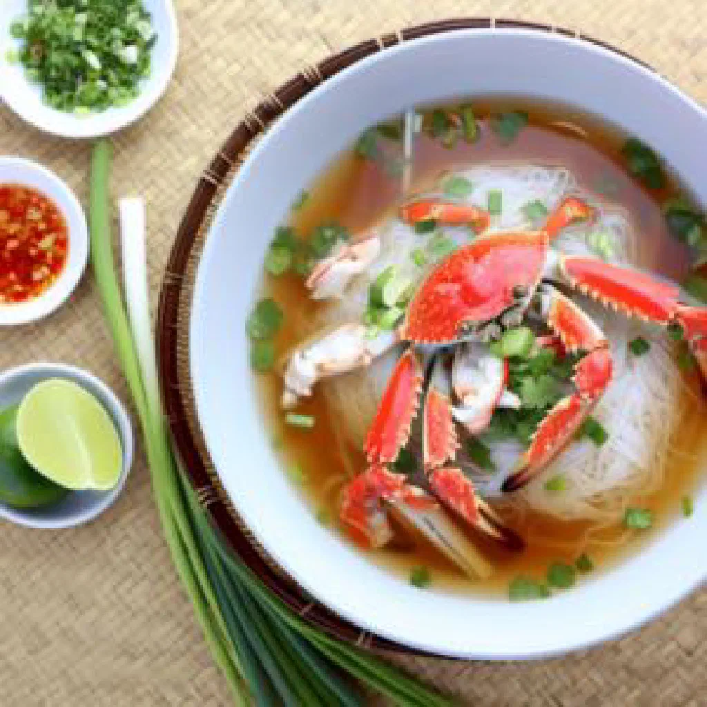 Bowl of Vietnamese crab noodle soup with thick rice noodles and fresh herbs