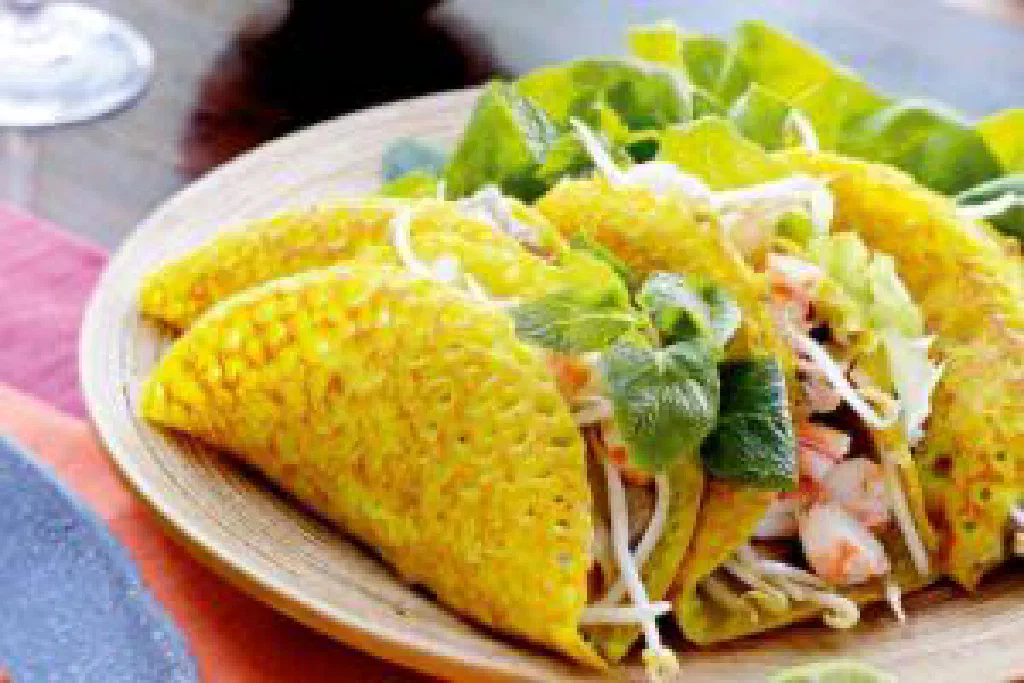 Crispy golden Vietnamese banh xeo pancake filled with pork and fresh herbs